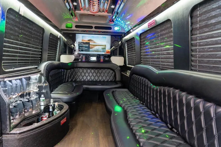 The interior of a stretch limousine, leather bench seating under coloured ceiling lighting