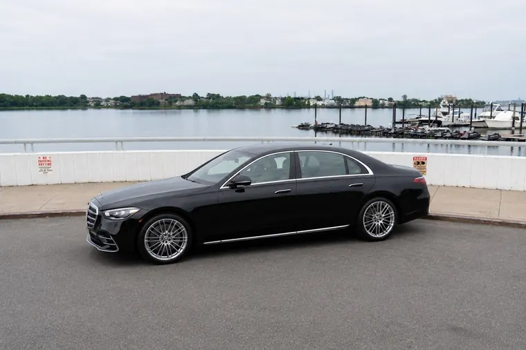 A black Mercedes-Benz S-Class parked on the waterfront with the Manhattan skyline behind it